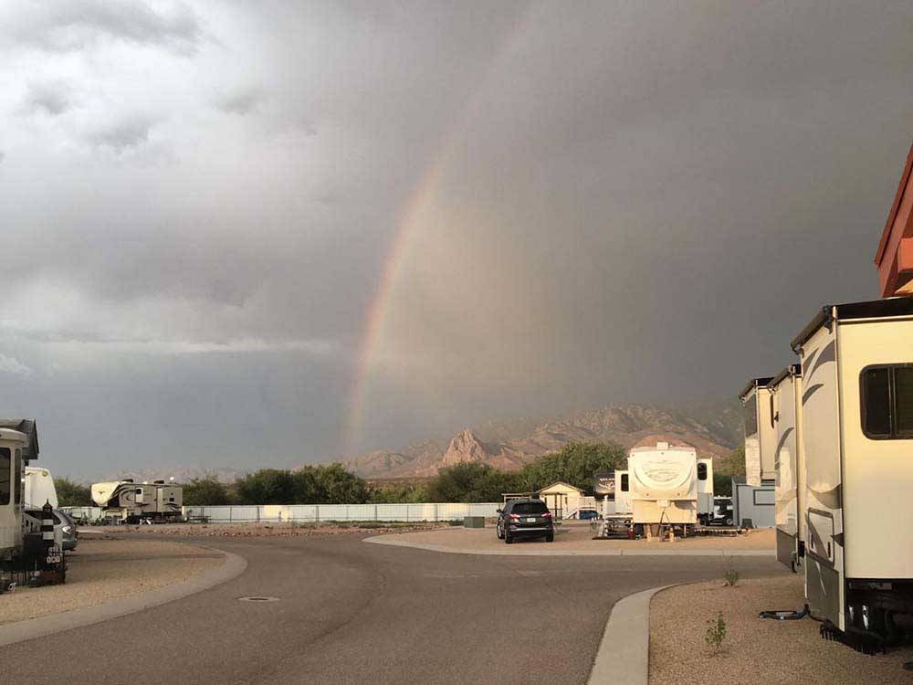 Rainbow arches over desert RV campground with mountains in background at DE ANZA RV RESORT