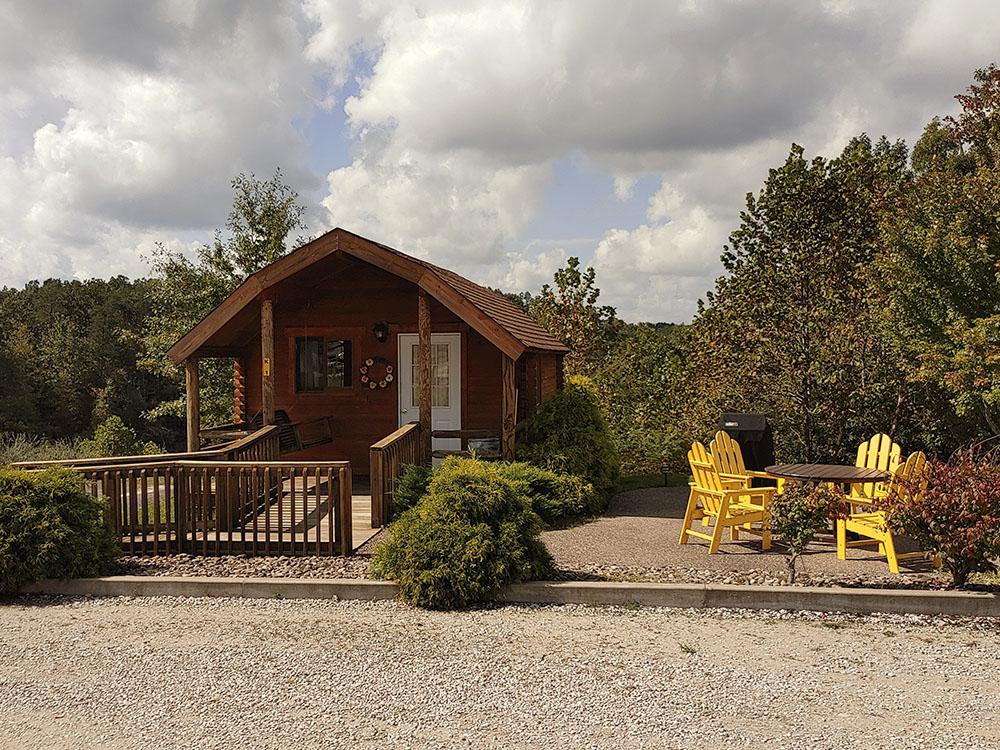 A rental cabin with Adirondack seating in front at ASHLAND/HUNTINGTON WEST KOA HOLIDAY