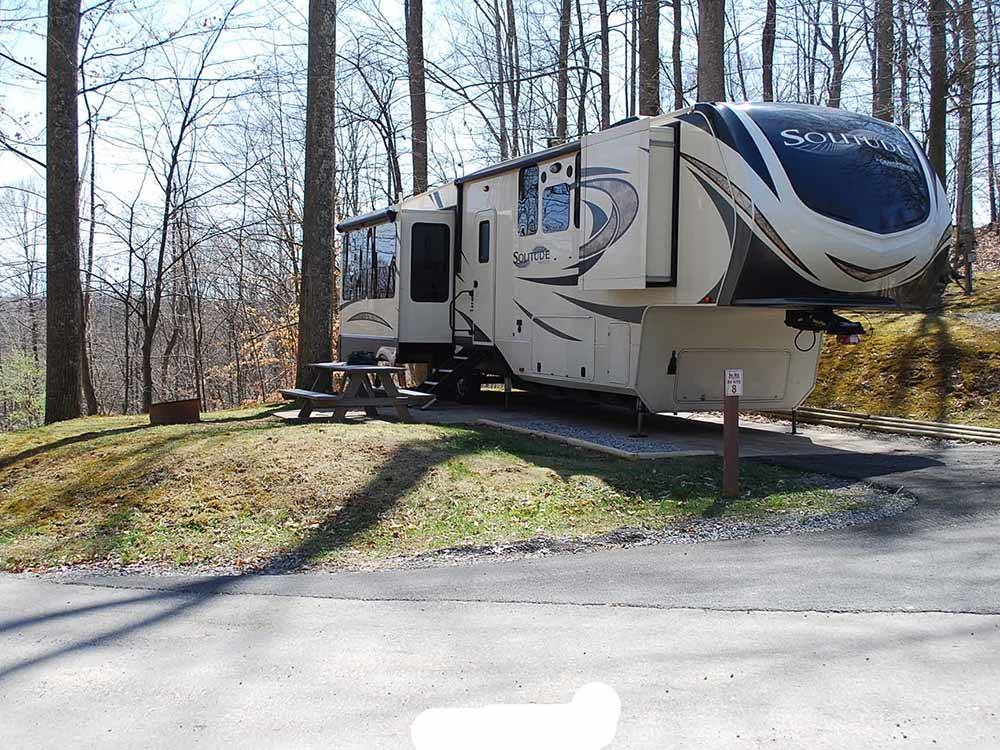 A fifth wheel trailer in a paved RV site at RIFRAFTERS CAMPGROUND