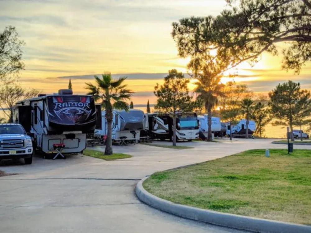 RVs parked on paved sites at sunset at On The Lake RV Resort