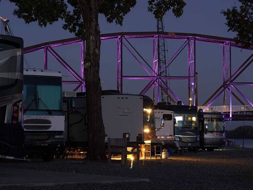 A line of RV sites with the bridge lit up in purple in the background at DOWNTOWN RIVERSIDE RV PARK