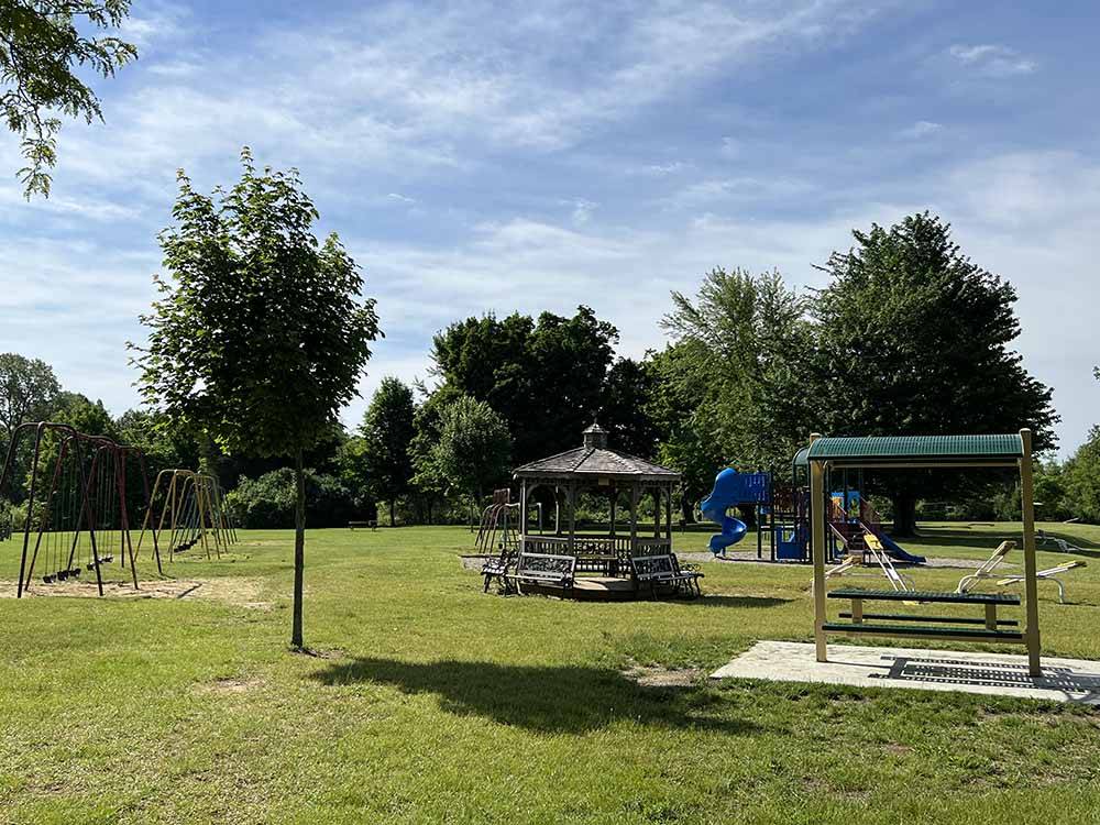 Swings and a gazebo in the grass at SOMERSET BEACH CAMPGROUND & RETREAT CENTER