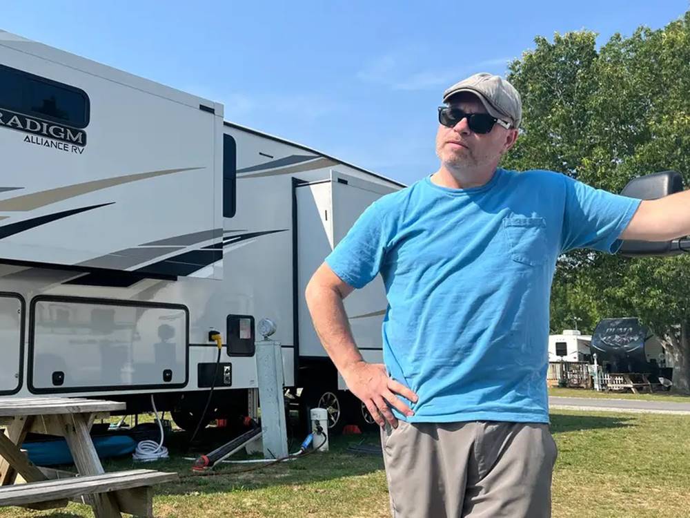 A man standing in front of a 5th wheel at Tranter's Creek Resort & Campground