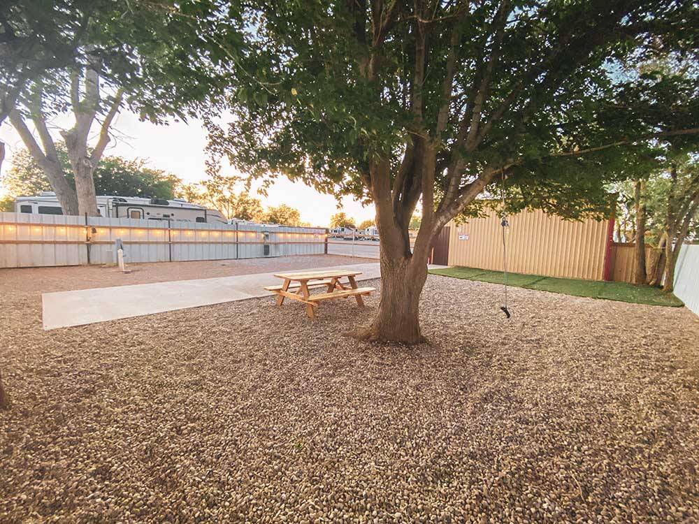 A paved site with a bench next to a tree at TRAILER VILLAGE RV PARK