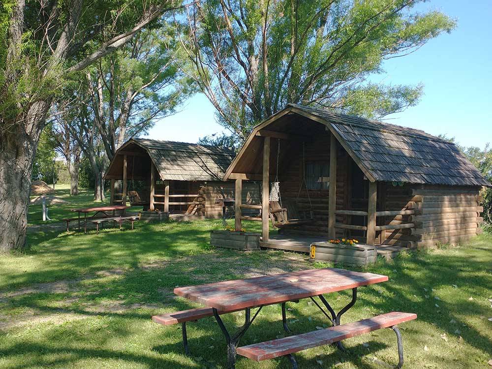 Wooden cabins under tall trees at WYLIE PARK CAMPGROUND & STORYBOOK LAND