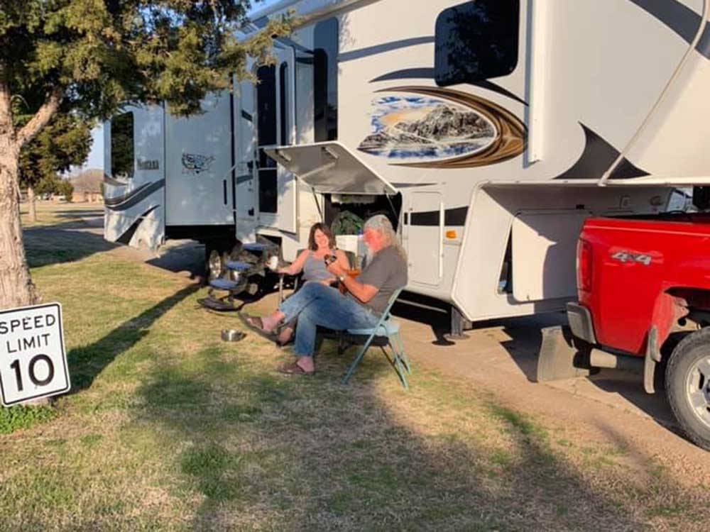 Couple sitting in chairs next to their RV at CEDAR VALLEY RV PARK