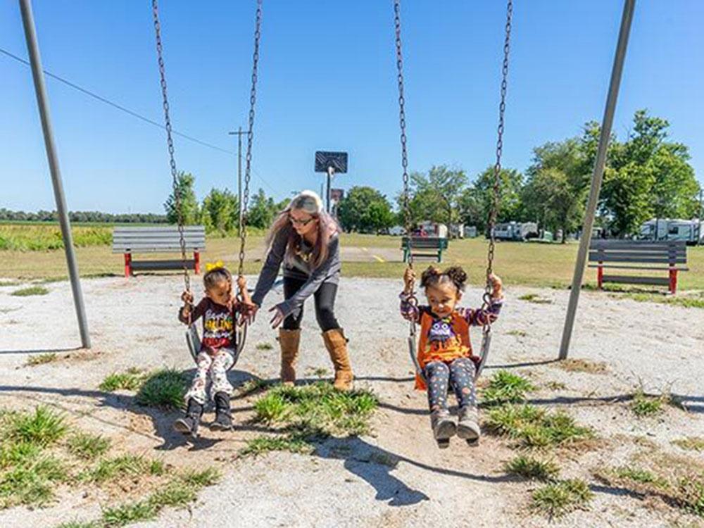 Two kids on the swings being pushed by their mom at SWAN CREEK COMMUNITY (MHP)