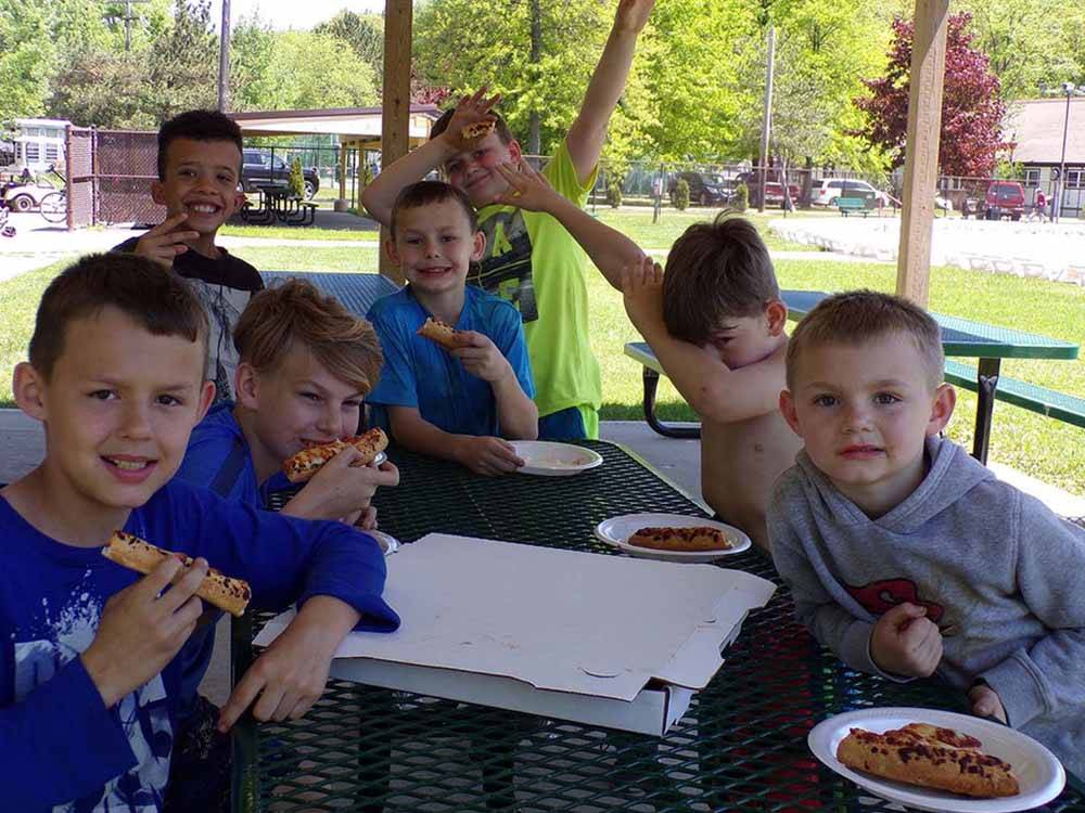 A bunch of kids eating pizza at MOUNTAIN PINES CAMPGROUND