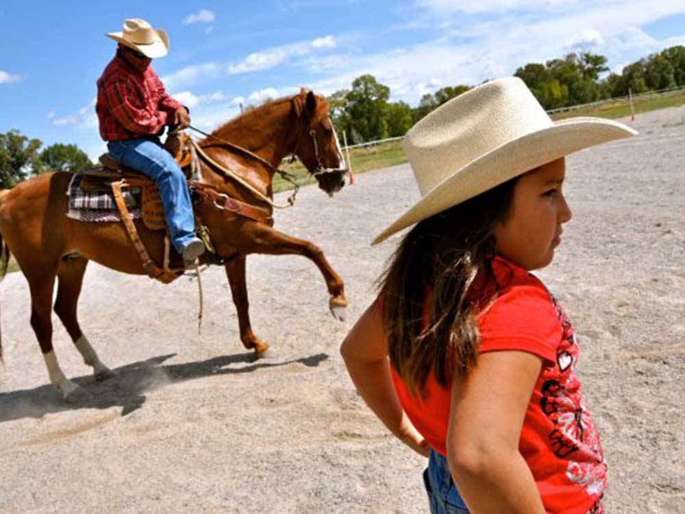 A girl in a cowboy hat standing in front of a horse at SKY UTE FAIRGROUNDS & RV PARK