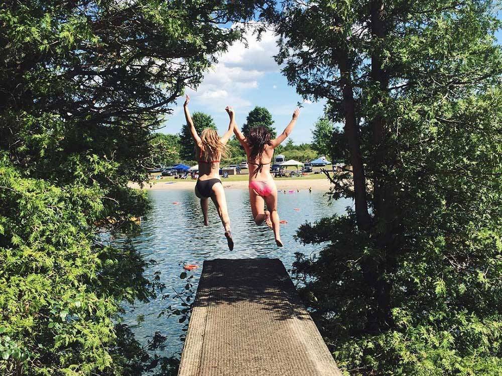 A couple of girls jumping off the dock at EMERALD LAKE TRAILER RESORT & WATERPARK