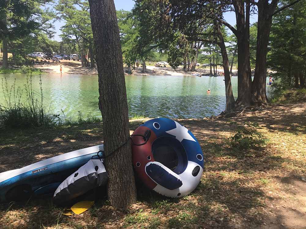 Inflatable water toys leaning against a tree by the river at PARKVIEW RIVERSIDE RV PARK