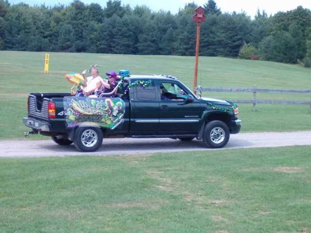 A truck with people in the back dressed in Mardi Gras decor at ADIRONDACK GATEWAY CAMPGROUND