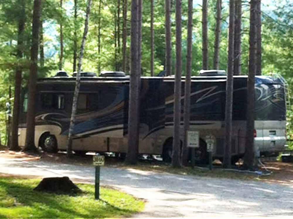 A motorhome parked in a gravel site at SCHROON RIVER CAMPGROUND & LODGING