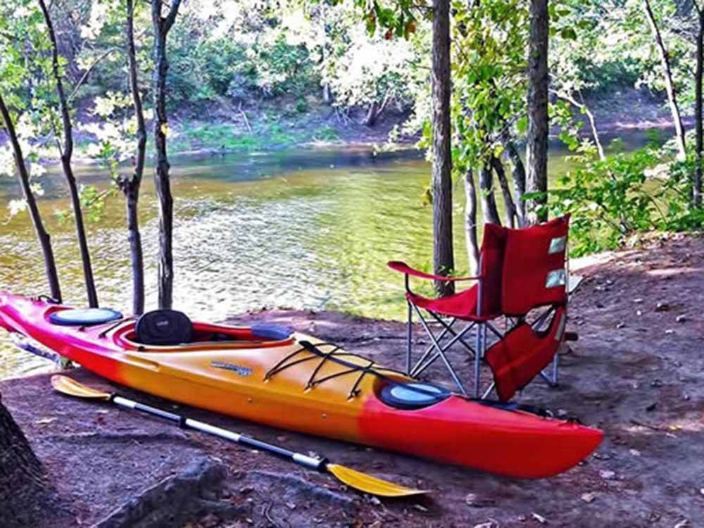 A kayak and chair next to the river at SCHROON RIVER CAMPGROUND & LODGING