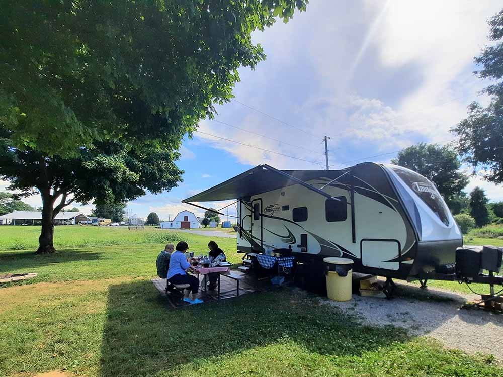 A family eating outside of their trailer at WHITE ACRES CAMPGROUND