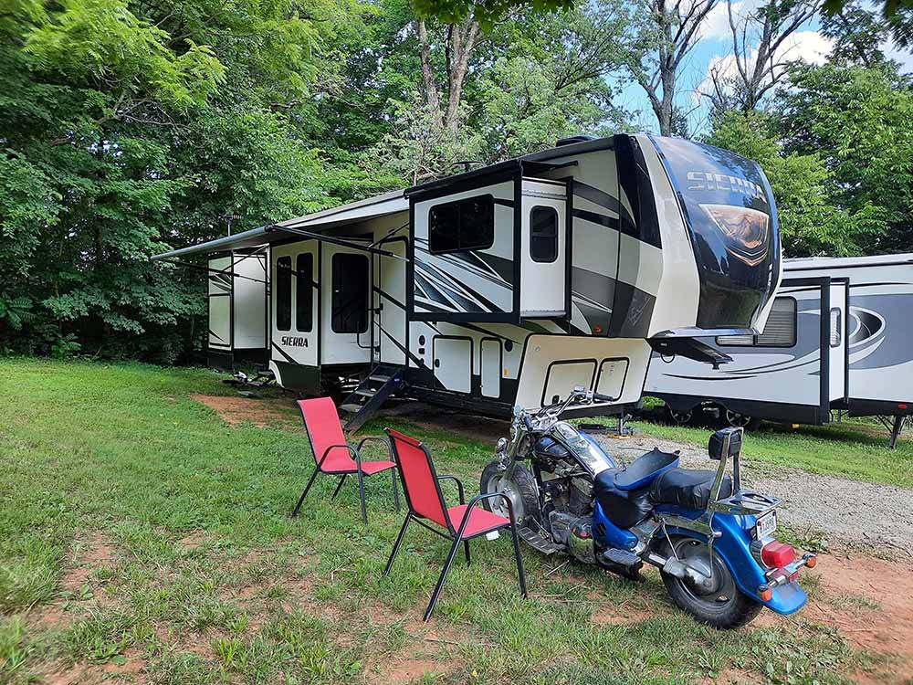 A motorcycle and trailer in an RV site at WHITE ACRES CAMPGROUND