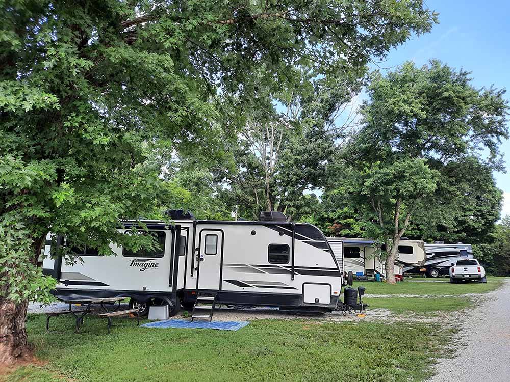 A travel trailer in a gravel RV site at WHITE ACRES CAMPGROUND