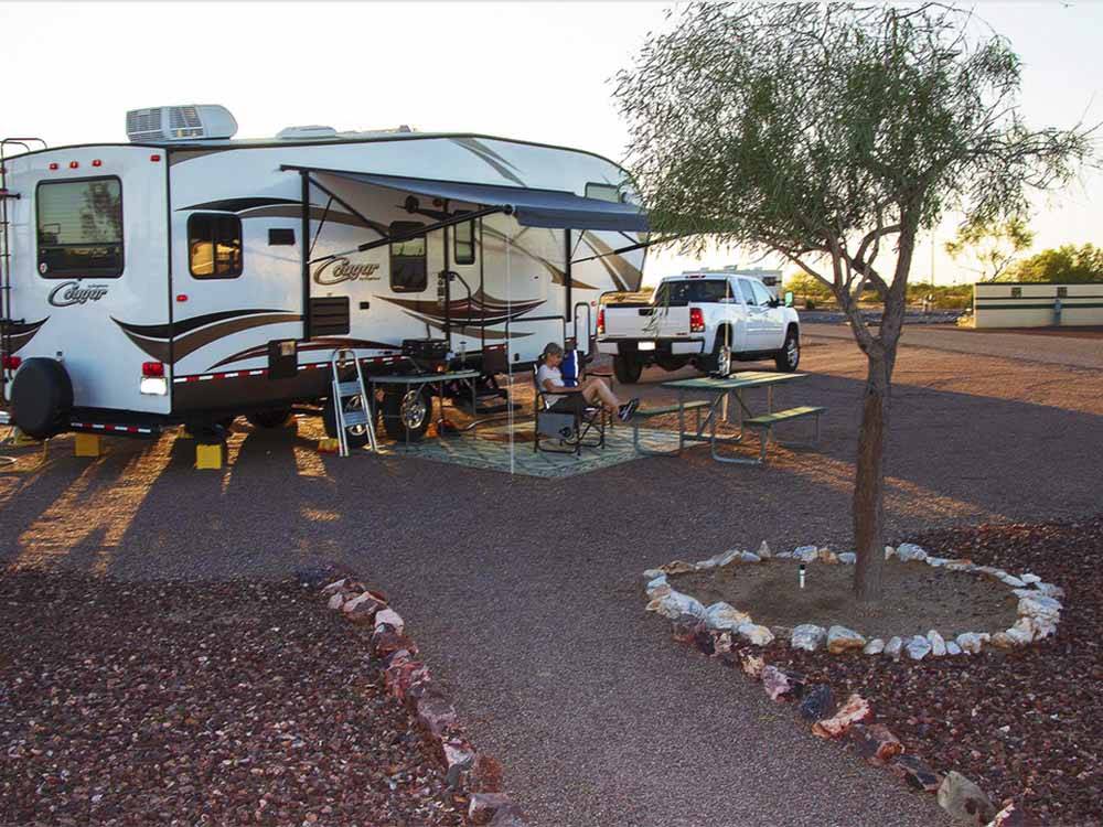 People sitting outside of their fifth wheel trailer at SONORAN DESERT RV PARK