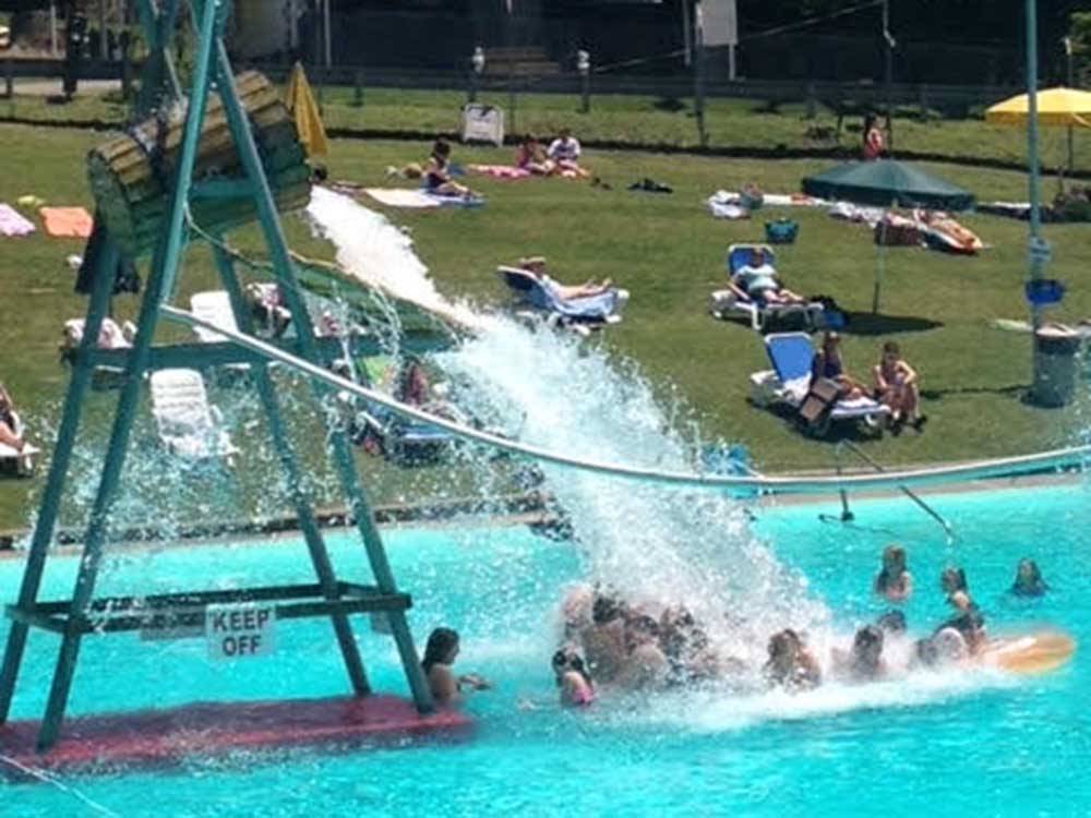 Water splashing on kids in the swimming pool at PINE COVE BEACH CLUB & RV RESORT