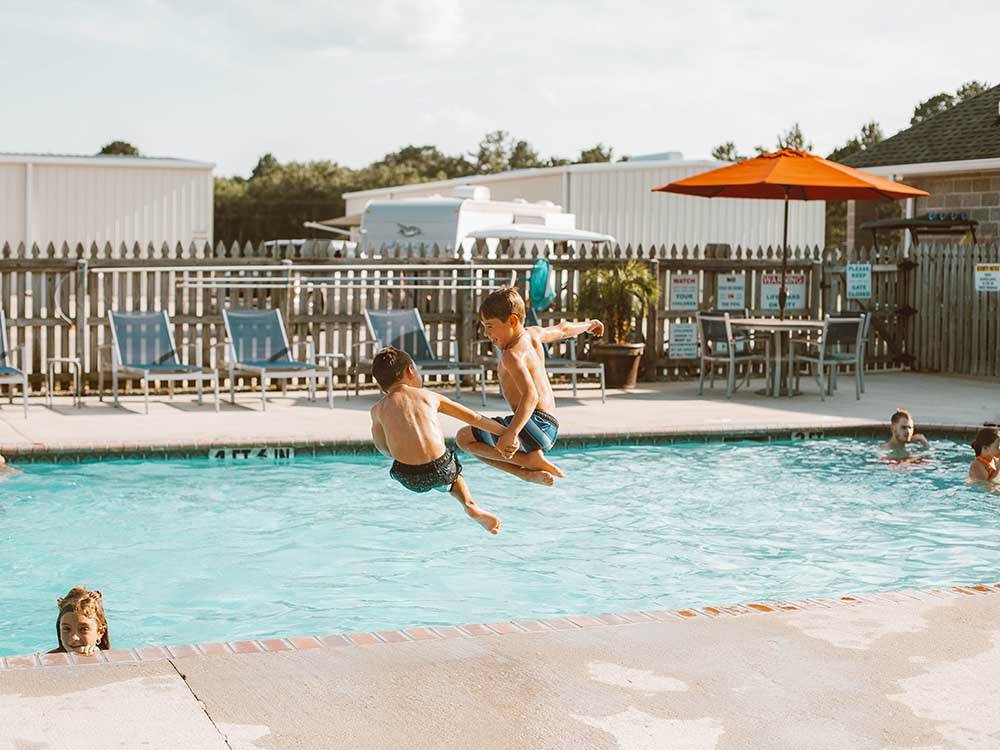 A couple of boys jumping into the pool at LAKESIDE RV PARK