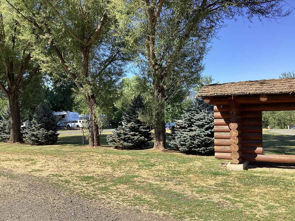 Large green trees next to a wooden building at LONG CAMP RV PARK
