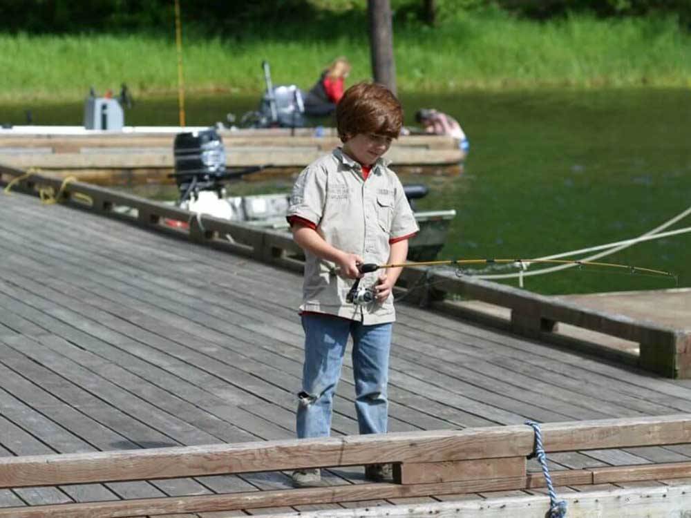 A small boy fishing off the dock at LOON LAKE LODGE & RV RESORT