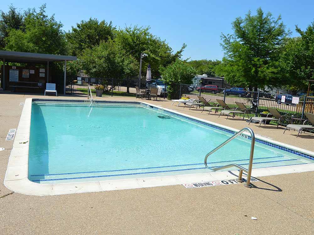 Large swimming pool with lounge chairs at TEXAN RV RANCH