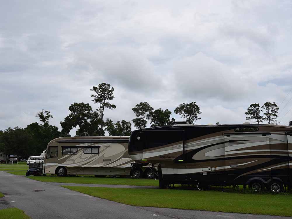 A row of motorhomes with grass at WILD FRONTIER RV RESORT
