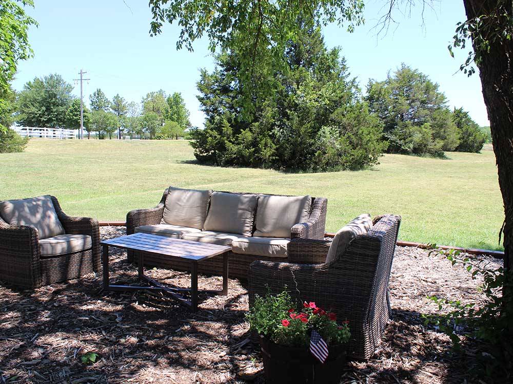An outdoor seating area under trees at ARBUCKLE RV RESORT