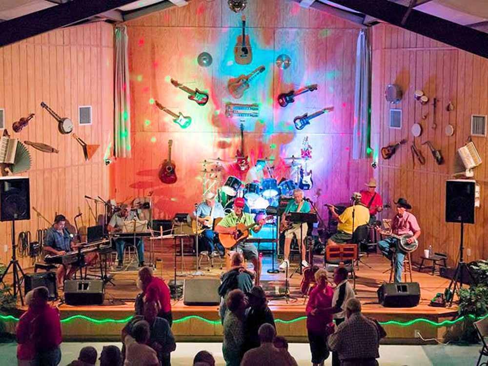 A band playing on a large indoor stage at ROCKY HOCK CAMPGROUND