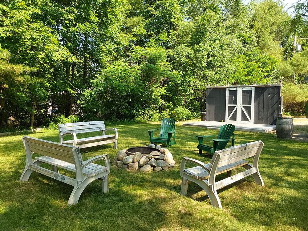 Fire pit with wood benches and chairs at CAMP AT NEWFOUND LAKE