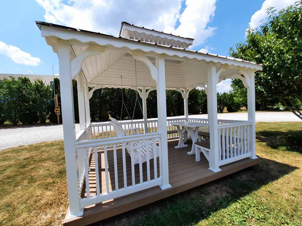 A white gazebo with a swinging bench at CAVE COUNTRY RV CAMPGROUND