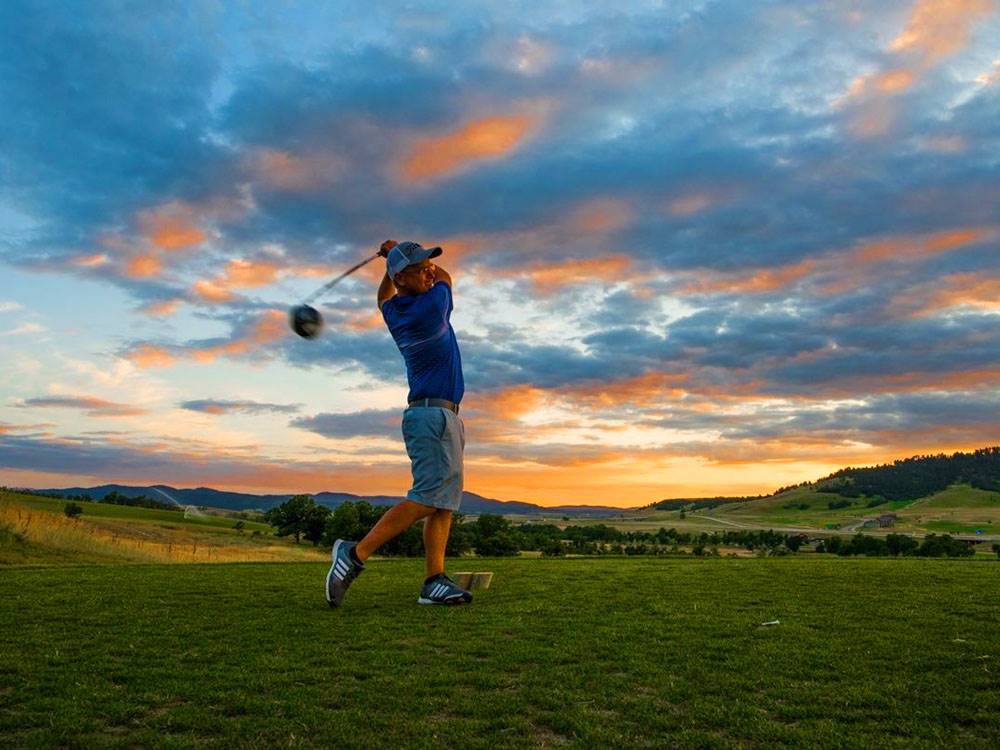 Man golfing at sunset at ELKHORN RIDGE RV RESORT & CABINS