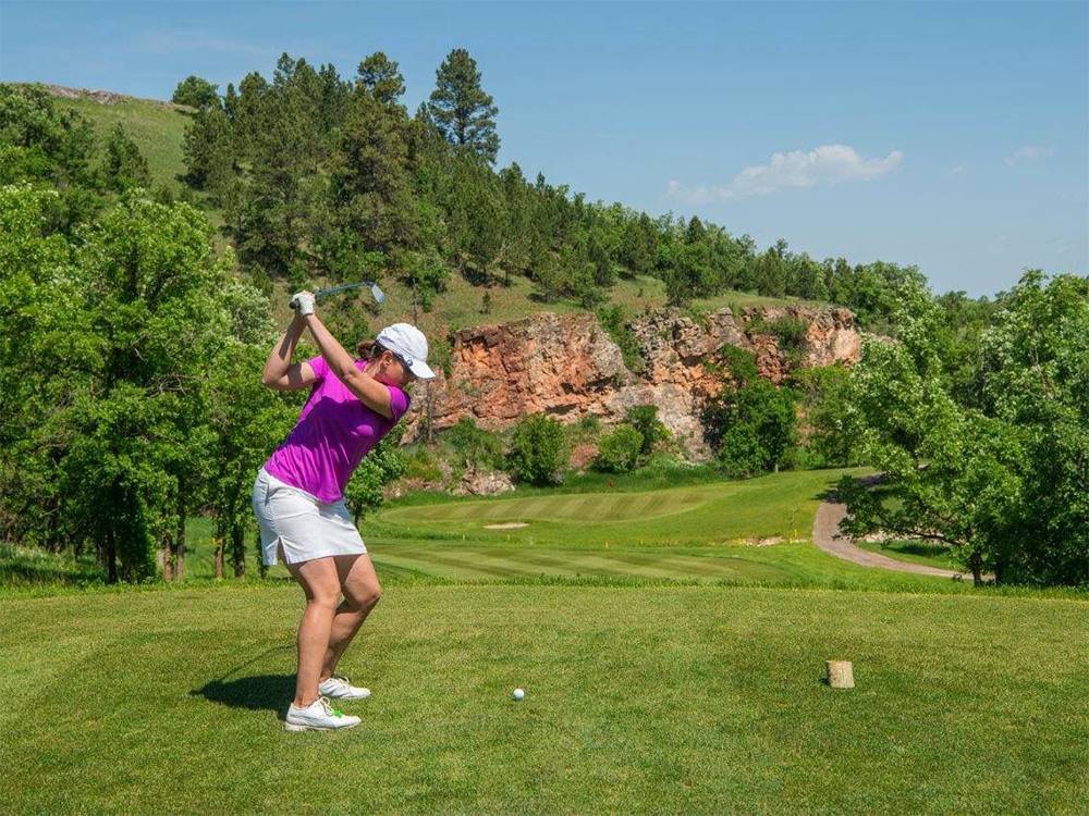 A female golfer taking a tee shot at Elkhorn Ridge RV Resort & Cabins