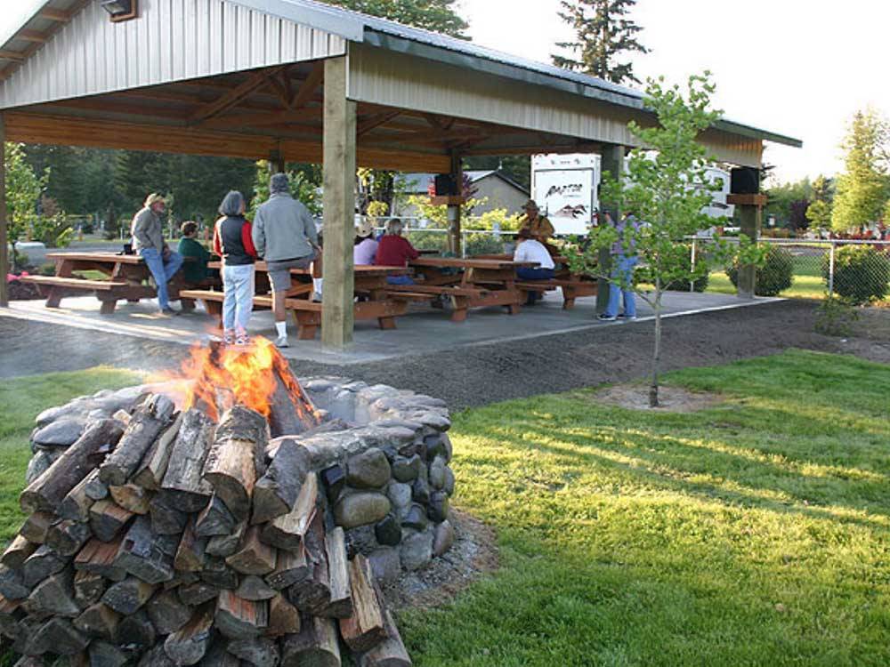 The fire pit with a fire in front of an outdoor covered sitting area at TOUTLE RIVER RV RESORT