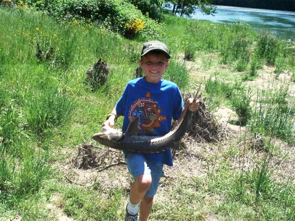 A young boy holding a fish at TOUTLE RIVER RV RESORT