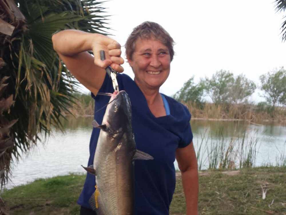 A woman holding a fish she caught at LAZY PALMS RANCH RV PARK