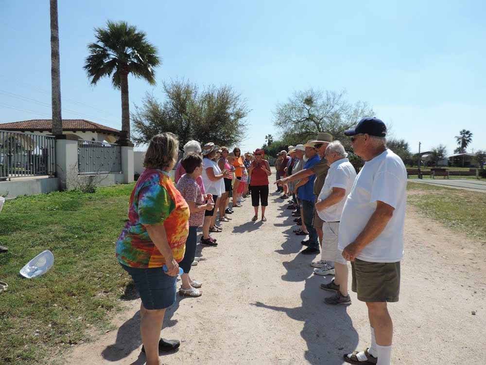A woman walking between a line of people at LAZY PALMS RANCH RV PARK