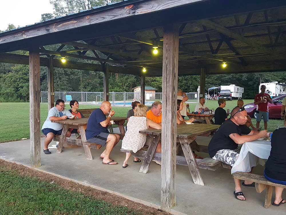 A group of people eating in a pavilion at DAN RIVER CAMPGROUND