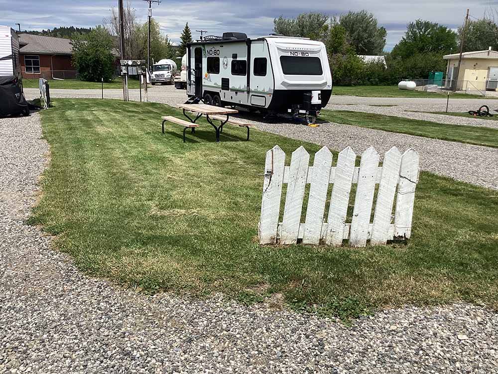 A white picket fence next to an RV site at OLD WEST RV PARK