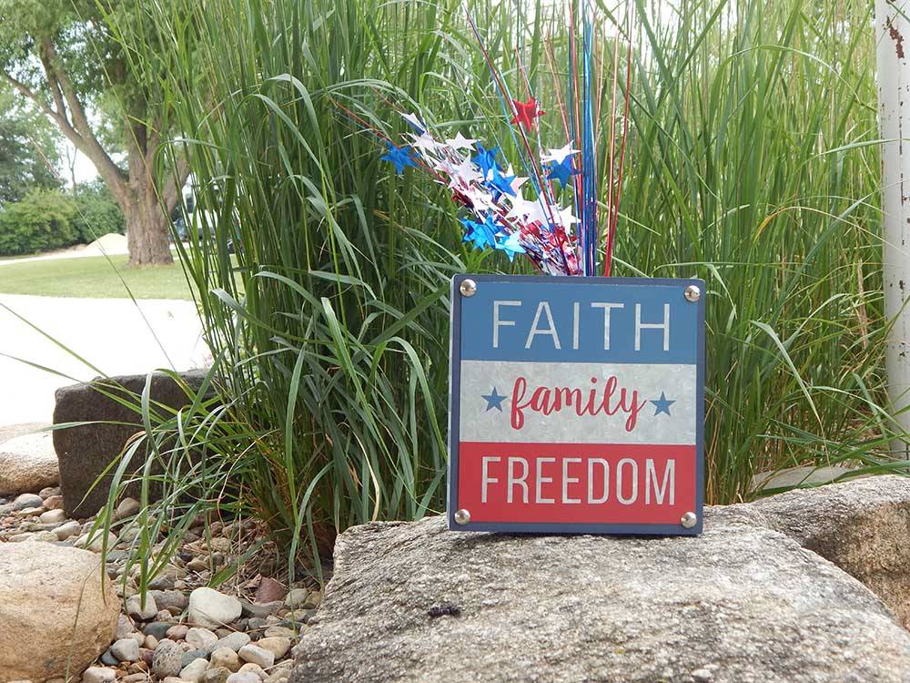 A sign on a rock that says Faith, Family and Freedom at LAKESHORE RV RESORT & CAMPGROUND