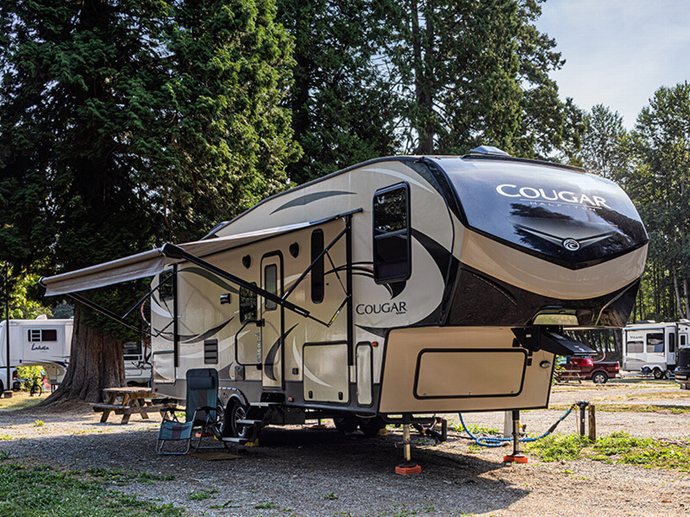A fifth wheel RV near tall trees at Sun Retreats Birch Bay