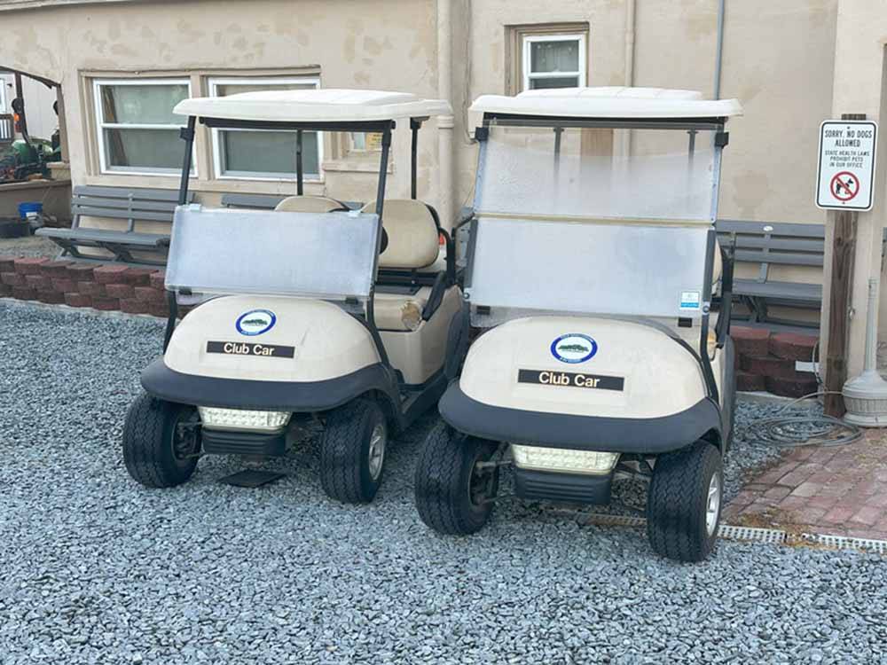 Two golf carts parked next to a building at FOUR OAKS LODGING & RV RESORT