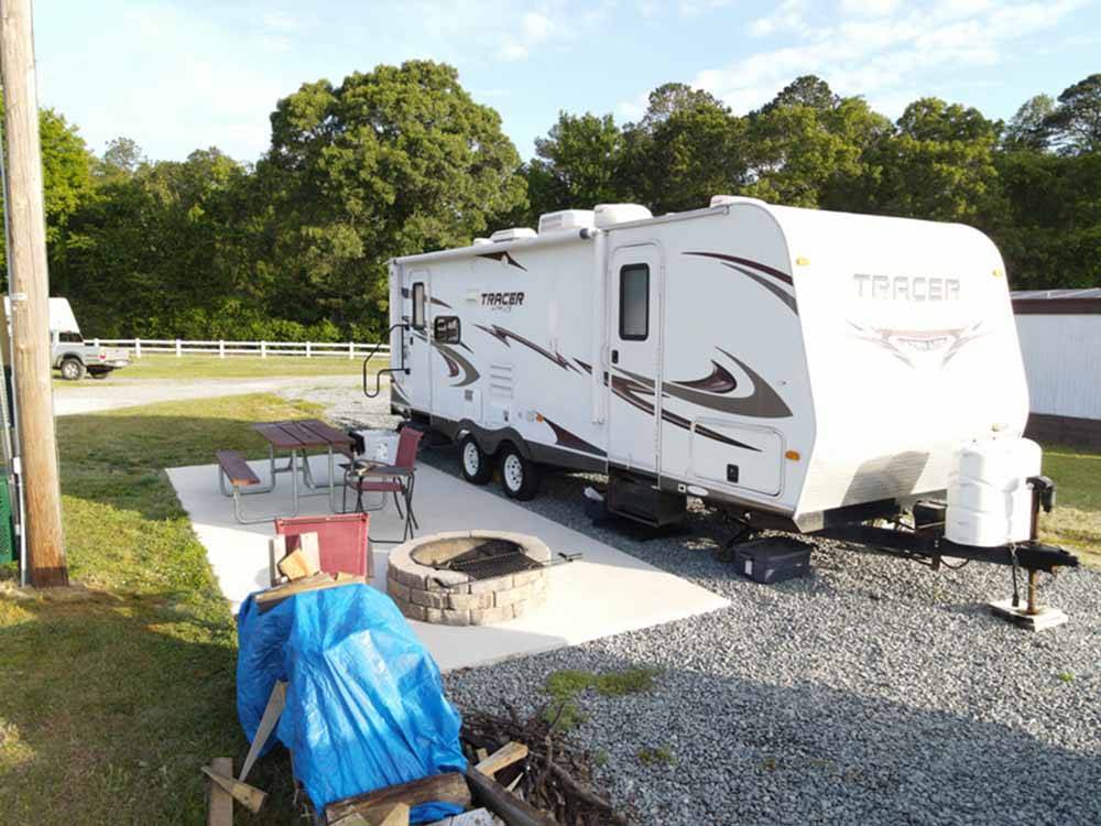 A travel trailer parked in a gravel site at FOUR OAKS LODGING & RV RESORT