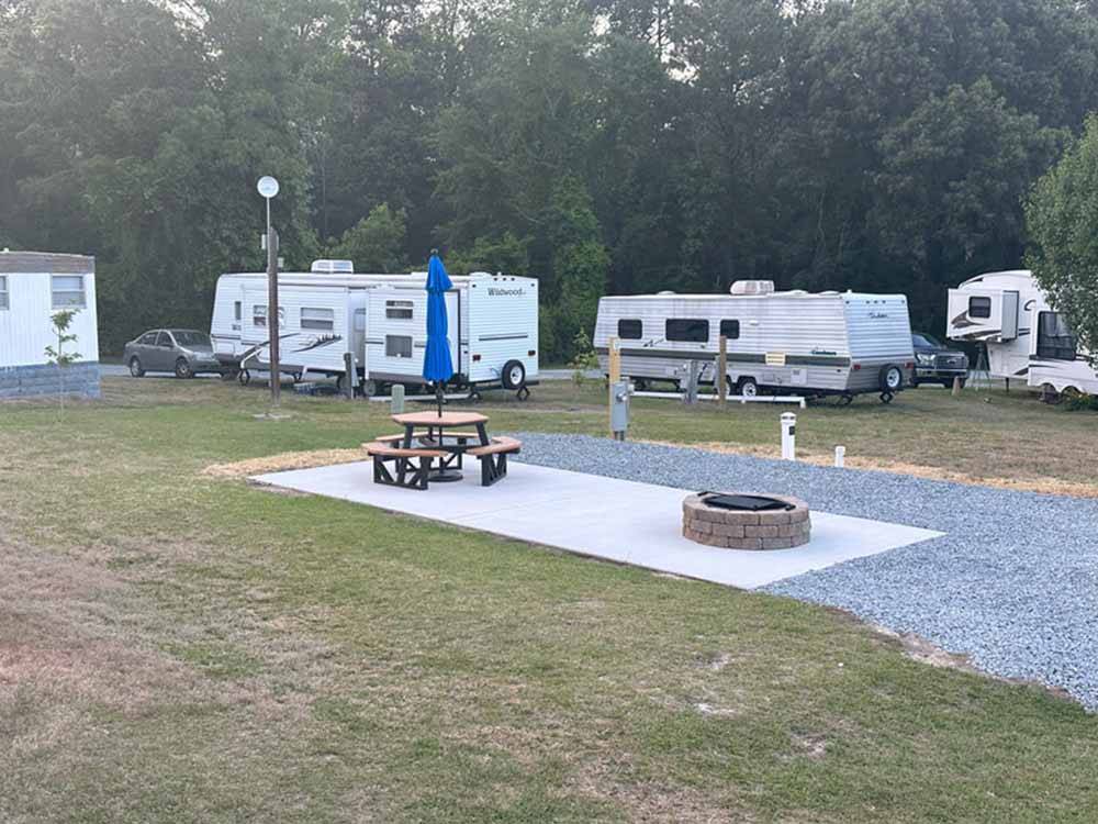 An empty gravel site with a table and fire pit at FOUR OAKS LODGING & RV RESORT