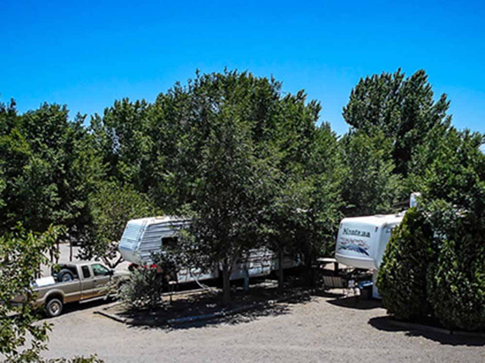A couple of trailers parked between trees at KIVA RV PARK & HORSE MOTEL