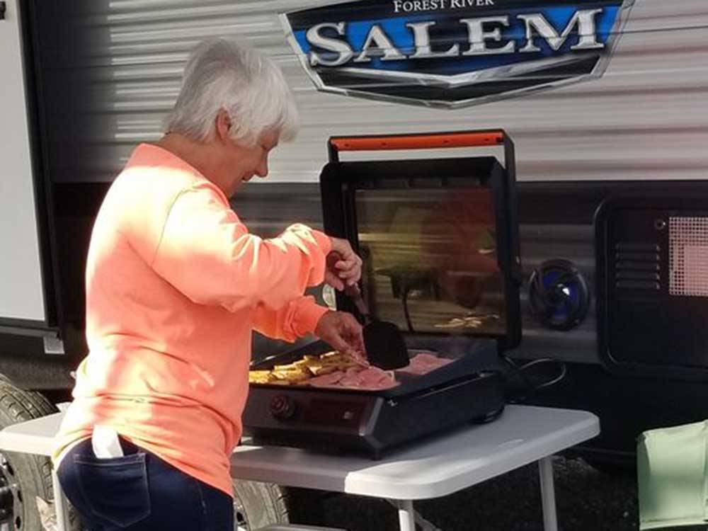 Woman grilling outside her RV at COYOTE VIEW RV PARK & RV REPAIR