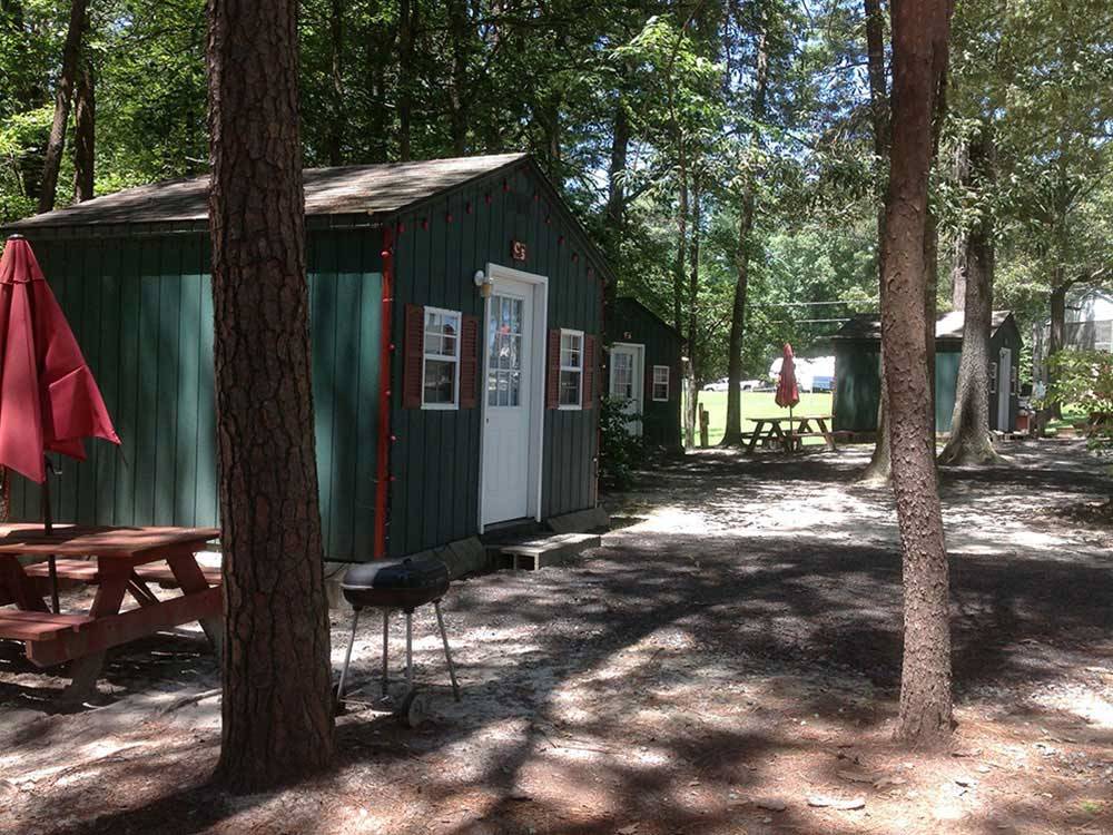 Green and red painted cabins with picnic tables at R & D FAMILY CAMPGROUND