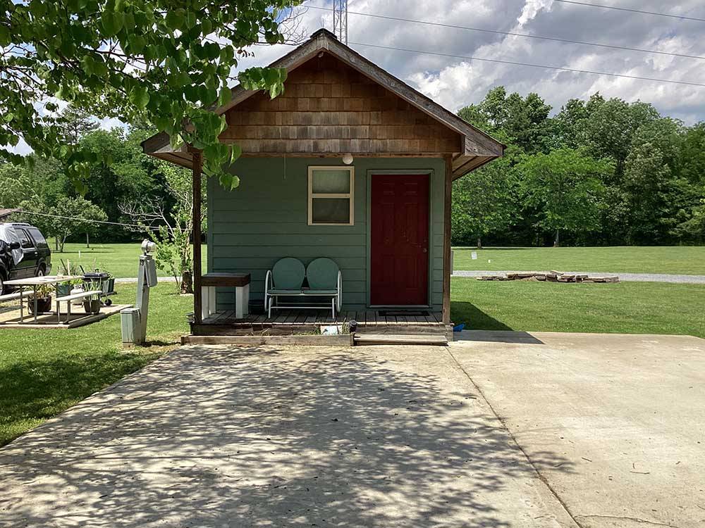 A green rental cabin with a seat in the front at WILLS CREEK RV PARK
