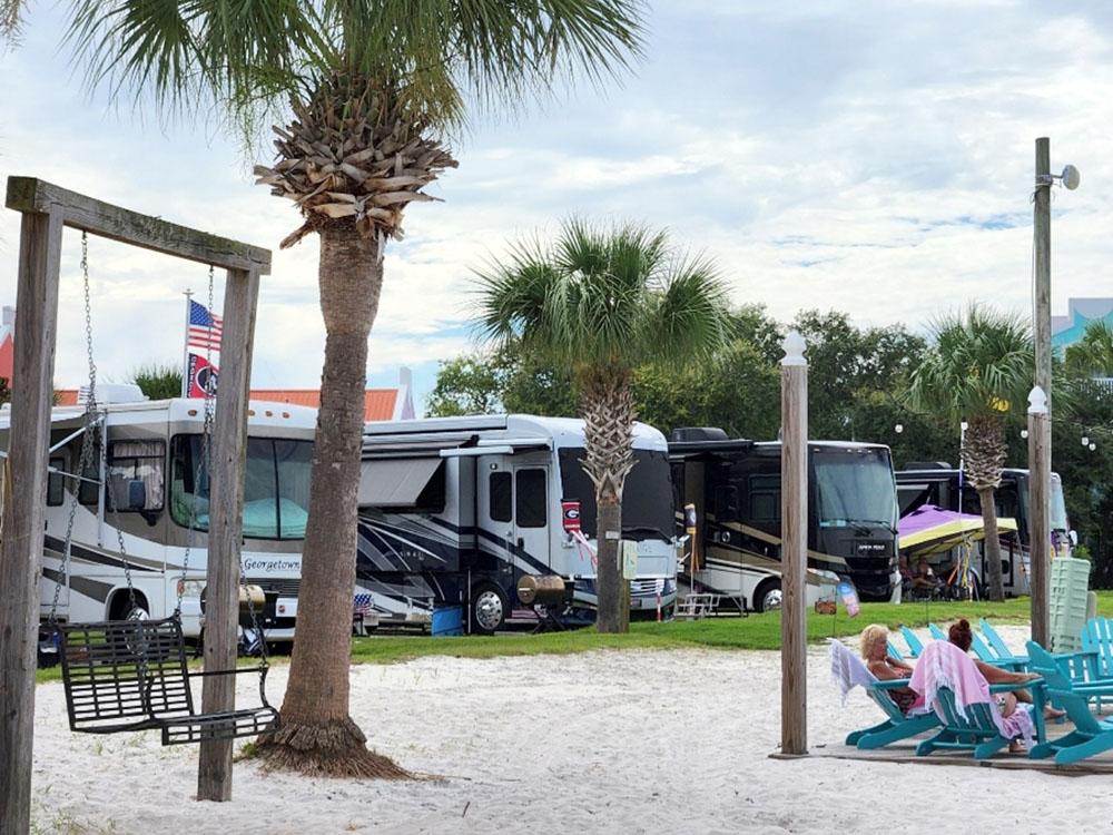 People relaxing in Adirondack chairs near the dock at PERDIDO KEY RV RESORT